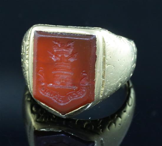 A 19th century yellow metal and carnelian set signet ring, the matrix carved with castle turret and motto, size J/K.